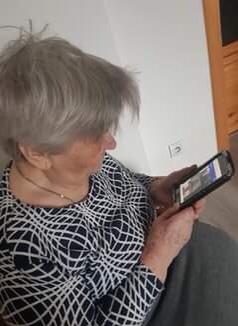 Na zdjęciu kobieta w podeszłym wieku wpatrzona w telefon komórkowy.