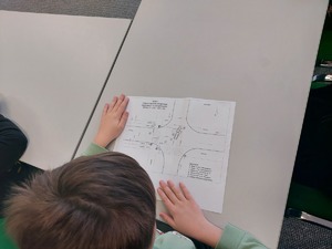uczeń ogląda szkic miejsca zdarzenia na kartce papieru.