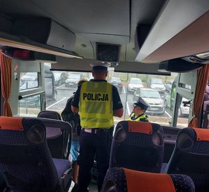 widzimy policjantów kontrolujących kierowcę w autobusie.