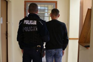 Policjant stoi przy zatrzymanym.