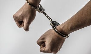 zdjęcie poglądowe - ręce mężczyzny skute kajdankami.
