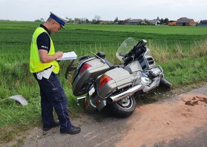 Policjant wykonuje oględziny uszkodzonego motocykla.