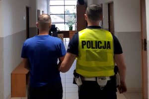 Policjant prowadzi zatrzymanego.