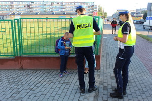 chłopiec ogląda element odblaskowy w obecności policjantów.