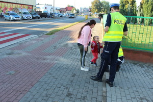 kobieta z dziewczynką na chodniku oraz policjanci.