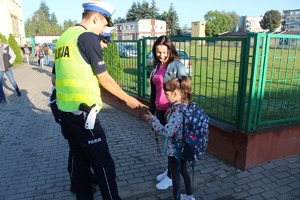 dziewczynka otrzymuje od policjanta element odblaskowy.