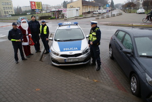 policjanci a obok nich Święty Mikołaj i policyjny radiowóz.