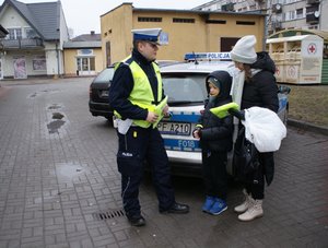 policjant ruchu drogowego wręcza element odblaskowy.