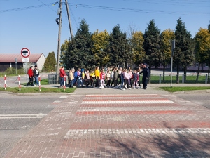 uczniowie z policjantem w rejonie przejścia dla pieszych.