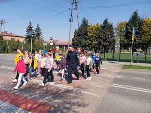 policjant przeprowadza dzieci przez przejście dla pieszych.