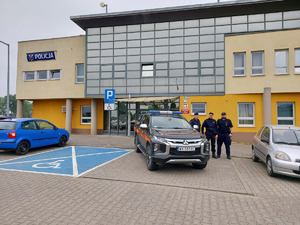 policjant i funkcjonariusze Służby ochrony Kolei na tle Komendy Powiatowej Policji w Wieruszowie.