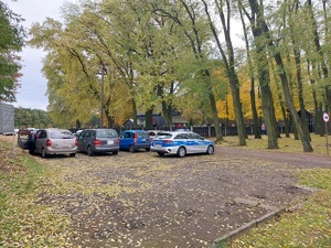 parking przy cmentarzu w tle radiowóz.