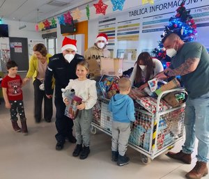 dzieci obdarowywane prezentami przez policjanta i osoby biorące udział w akcji.