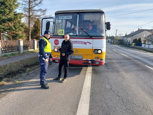 policjant wręcza serduszko kierującemu autobusu.
