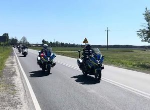 widzimy patrol drogówki na motocyklach, a za nimi kolumna motocyklistów.