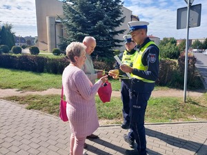 policjanci wręczają odblaski osobom starszym.