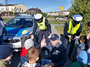 policjanci wręczają odblaskowe misie dzieciom.