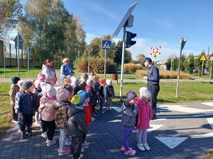 policjant rozmawia z dziećmi na skrzyżowaniu miasteczka ruchu drogowego.