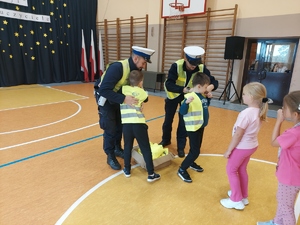 policjanci wręczają kamizelki odblaskowe dzieciom.