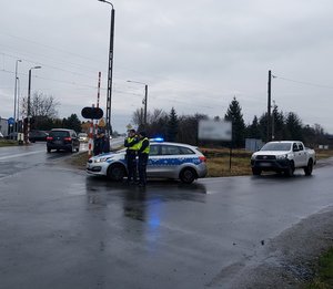 widzimy policjantów oraz funkcjonariuszy Straży Ochrony Kolei podczas wspólnych działań w rejonie przejazdu kolejowego.