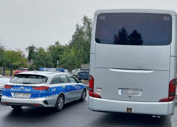 widzimy autobus, obok stojący radiowóz i samochody osobowe.