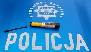 widzimy urządzenie do badania stanu trzeźwości na masce radiowozu i napis Policja Pomagamy i Chronimy.