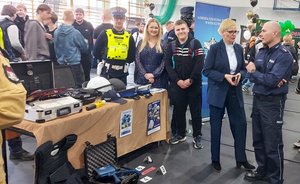 widzimy policjantów przy stoisku promocyjnym wraz z uczestnikami.