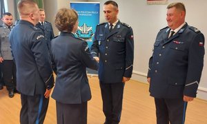 widzimy komendantów składających gratulacje policjantom pomieszczeniu.