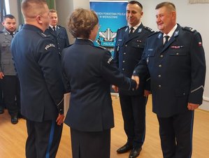 widzimy komendantów składających gratulacje policjantom pomieszczeniu.