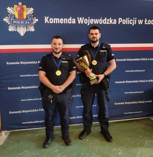 widzimy policjantów z Wieruszowa, którzy zajęli pierwsze miejsce, jeden z nich trzyma w ręku puchar.