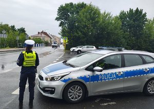 widzimy policjantkę na tle radiowozu oznakowanego w rejonie przejścia dla pieszych.