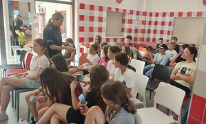 policjantka rozdaje ulotki dzieciom.