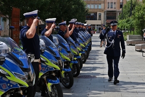 na zdjęciu w rzędzie stoją motocykle a przy nich policjanci