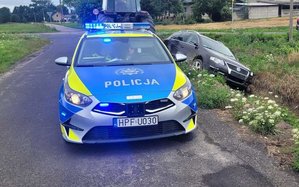 na zdjęciu widać radiowóz oznakowany i pojazd w rowie
