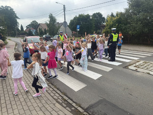 widzimy dzieci przechodzące po przejściu dla pieszych w obecności policjantów.