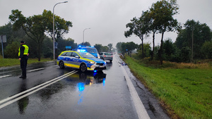 widzimy policjanta kierującego ruchem podczas wypadku drogowego z udziałem samochodu osobowego i rowerzysty.