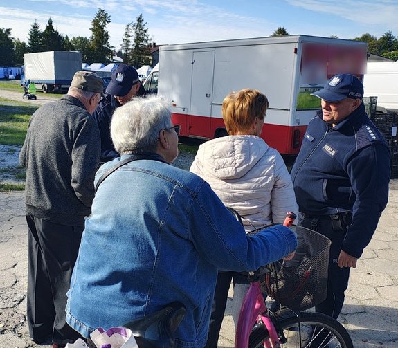 widzimy policjantów podczas rozmowy z osobami na targowisku.