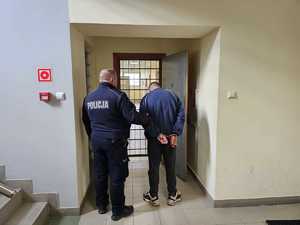 na zdjęciu widać policjanta oraz mężczyznę w kajdankach