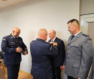 widzimy odznaczonego policjanta oraz wręczających odznaczenia.