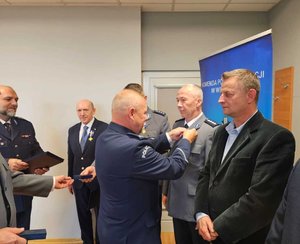 widzimy odznaczonego policjanta oraz wręczających odznaczenia.