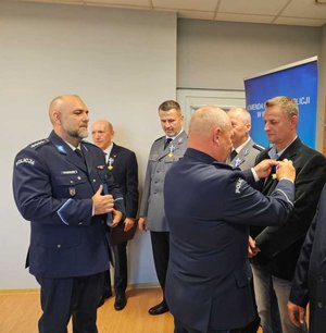 widzimy odznaczonego policjanta oraz wręczających odznaczenia.