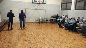 widzimy policjantów pokazujących chwyty obezwładniające oraz uczestników spotkania.