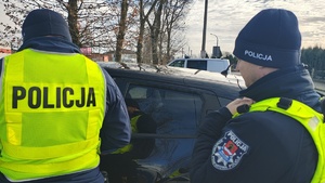 widzimy policjantów prowadzących kontrolę pojazdu.