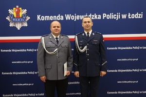 widzimy policjantów stojących na ściance Komendy Wojewódzkiej Policji w Łodzi.