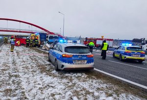 widzimy pojazdy biorące udział w wypadku i miejsce zdarzenia wraz z policjantami pracującymi na miejscu.
