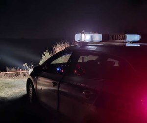 widzimy radiowóz stojący przy skarpie akwenu.