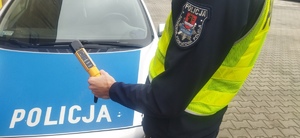 widzimy policjanta trzymającego urządzenie do badania stanu trzeźwości.