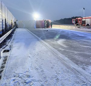 widzimy wywrócona ciężarówkę na boku i pracujące służby.