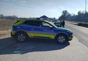 widzimy policjantów kontrolujących mężczyznę na tle policyjnego radiowozu.