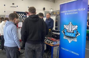 widzimy policjanta rozmawiającego z młodzieżą na spotkaniu profilaktycznym.